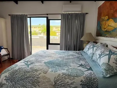 a bedroom with a bed with a blue comforter at Villa Luddy Beach & Relax in Juan Dolio