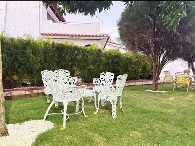 a group of white chairs and a table in a yard at Villa Luddy Beach & Relax in Juan Dolio