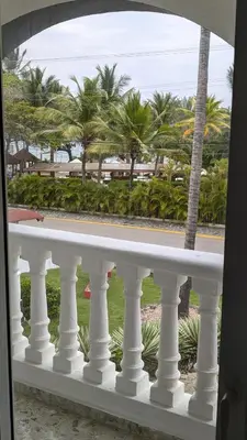 a white balcony with palm trees in the background at Cofresi Villas in Maggiolo