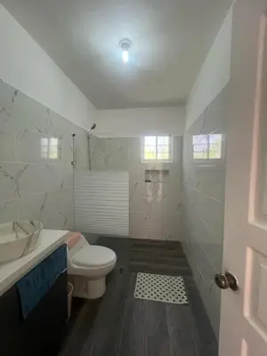 a white bathroom with a toilet and a sink at apartment for rent in Bayahibe