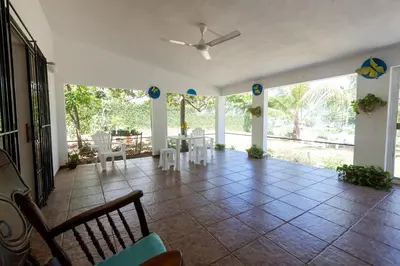 a living room with a ceiling fan and tables and chairs at Playa Grande House in Las Galeras