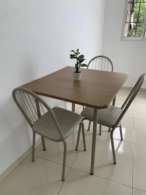 a wooden table with two chairs and a potted plant at Acogedor apartamento de 1 dormitorio cerca de la playa in Sosúa