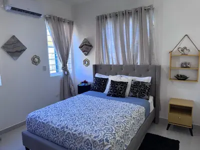 a bedroom with a bed with a blue comforter and pillows at Villa Tropical Paradise Pool Rooftop in San Felipe de Puerto Plata