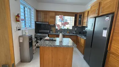 a kitchen with wooden cabinets and a stainless steel refrigerator at Villa Tropical Paradise Pool Rooftop in San Felipe de Puerto Plata