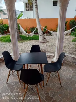 two chairs and a table in a courtyard with palm trees at Cerca de la playa apartamento familiar in Punta Cana
