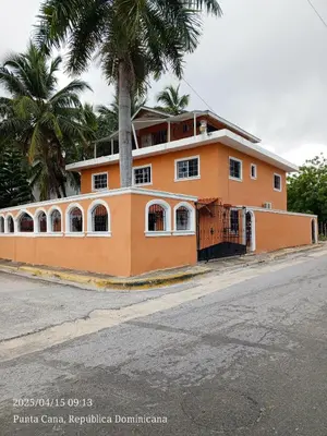 an orange building with a palm tree in front of a street at Cerca de la playa apartamento familiar in Punta Cana