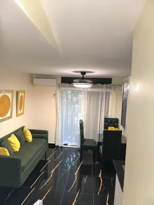 a living room with a green couch and two chairs at Escape en terrazas del caribe con psicina y playa in Boca Chica