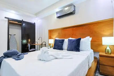 a bedroom with a large white bed with blue pillows at Cozy City Center 2BD Condo, in Santo Domingo