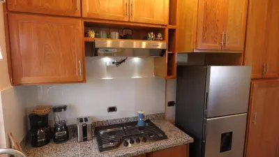 a kitchen with wooden cabinets and a stainless steel refrigerator at Juan Dolio Near Beach, Pool Cozy Stay in Villas del Mar
