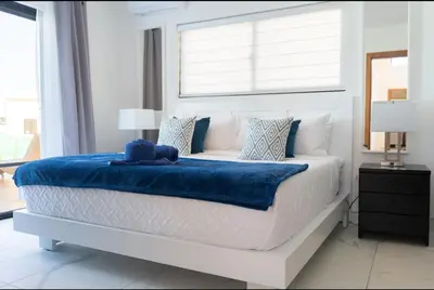 a white bedroom with a bed with a blue blanket at My luxury villa in Sosúa