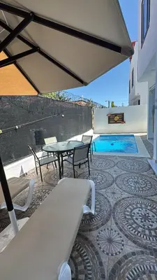 a patio with a table and chairs and a pool at Villa Tropical Paradise Pool Rooftop in San Felipe de Puerto Plata