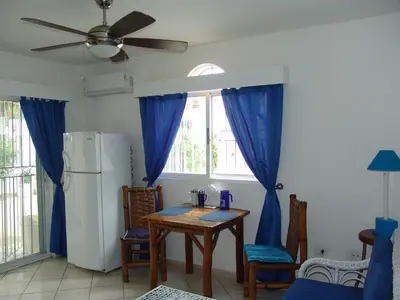 a kitchen with a table and a refrigerator with blue curtains at Surf & Stay Waveriders, Encuentro in Cabarete