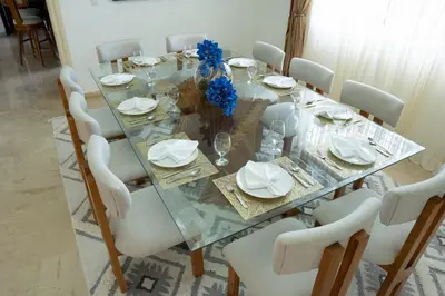 a glass dining table with white chairs and blue flowers at Villa La Dueña - Vista Hermosa Luxury Retreat, 5BR Villa with Pool, Swim-Up Bar, Jacuzzi, Chef's Kitchen, Fast Wi-Fi, Full AC, EV Charger and Solar Power, Ideal for Families & Groups in Cancino