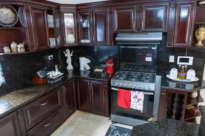 a kitchen with wooden cabinets and a stove top oven at Villa La Dueña - Vista Hermosa Luxury Retreat, 5BR Villa with Pool, Swim-Up Bar, Jacuzzi, Chef's Kitchen, Fast Wi-Fi, Full AC, EV Charger and Solar Power, Ideal for Families & Groups in Cancino