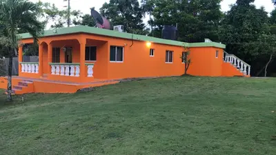 an orange house with a green roof on a field at paradise ranch san cristobal in San Cristóbal