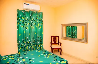 a bedroom with a bed and a chair and a window at Boom Ranch in Las Galeras