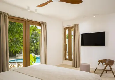 a bedroom with a bed and a flat screen tv at Tropical Roga Villa with Private Pool in Cabarete