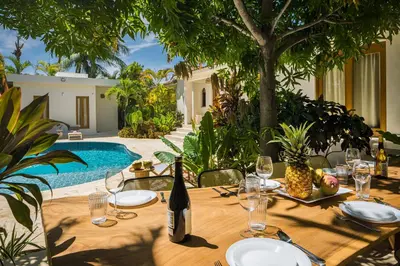 a wooden table with a bottle of wine and glasses at Tropical Roga Villa with Private Pool in Cabarete