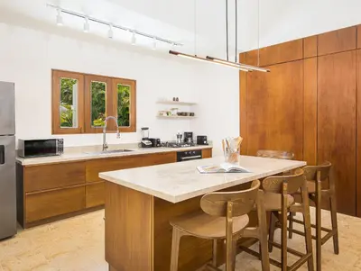 a kitchen with wooden cabinets and a island with bar stools at Tropical Roga Villa with Private Pool in Cabarete