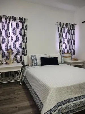 a bedroom with a bed with blue and purple curtains at Sunflower Bayahibe with pool in Bayahibe