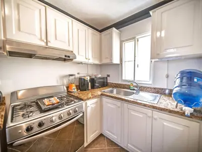 a kitchen with white cabinets and a stove and a sink at Garden Condos 7 - Central Apartment in Strip in Sosúa