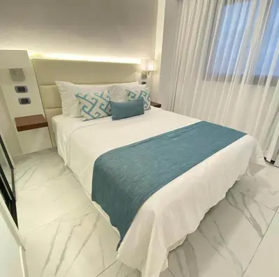 a bedroom with a large bed with blue and white pillows at Blue Paradise Punta Cana in Punta Cana