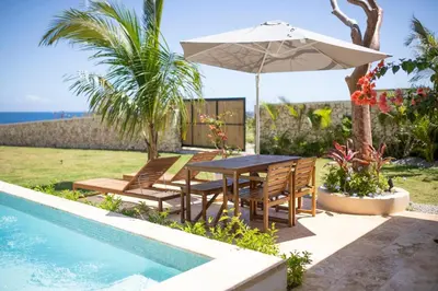 a table and chairs with an umbrella next to a swimming pool at Tesoro Villas in Río San Juan