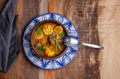 a bowl of soup on a plate with a spoon at Tesoro Villas in Río San Juan