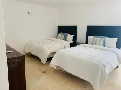 a room with two beds with white sheets and blue accents at Coson Bay in Las Terrenas