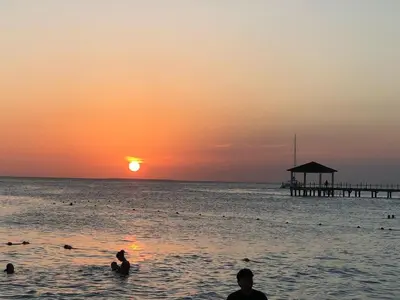 a group of people in the ocean at sunset at Cozy 2 bedroom Beach Apto in Bayahibe