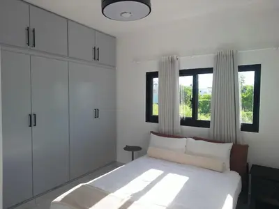 a white bedroom with a bed and two windows at Modern 3 BR Villa with pool in gated community in Sosúa