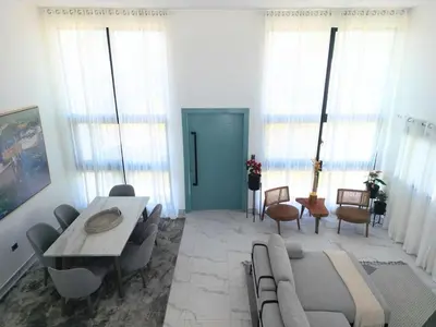 a living room with a table and chairs and windows at Modern 3 BR Villa with pool in gated community in Sosúa