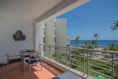 a balcony with a desk and a view of the ocean at Escape Beachfront Condo Costa del Sol Juan Dolio in Los Corrales