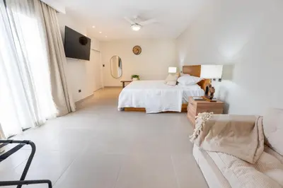 a white bedroom with a bed and a couch at Corner Penthouse with Ocean and City Views with a Content Creator Hub in Punta Cana