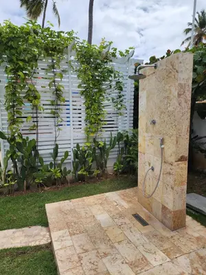 a stone shower in a yard with a fence at Zen Apartment in Punta Cana