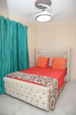 a bedroom with a large bed with green curtains at HERMOS APARTAMENTo in Santiago de los Caballeros