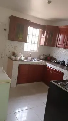 a kitchen with wooden cabinets and a sink and a window at Queen Bmazazhi Stay in San Pedro de Macorís