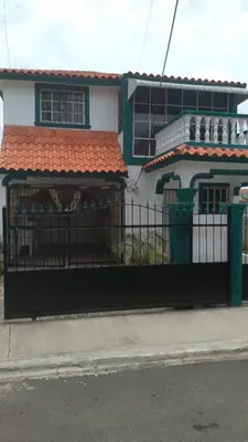 a fence in front of a house with a building at Queen Bmazazhi Stay in San Pedro de Macorís