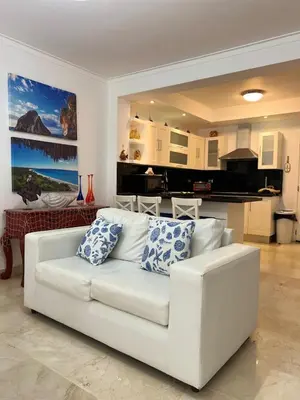 a white couch in a living room with a kitchen at Beautiful apartment in Playa Dorada in San Felipe de Puerto Plata
