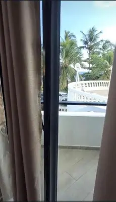 a window with a view of a pool and palm trees at Costa Azul Skibel 2 br in Santo Domingo