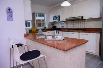 a kitchen with white cabinets and a granite counter top at Tranquil 3 Bedroom Apartment - Pool & Private Beach Access in Punta Cana