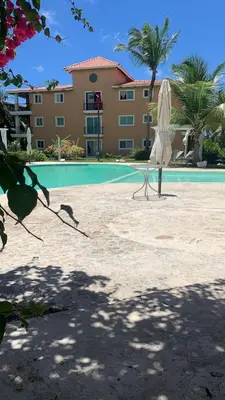 a white umbrella and a chair next to a pool at Tranquil 3 Bedroom Apartment - Pool & Private Beach Access in Punta Cana