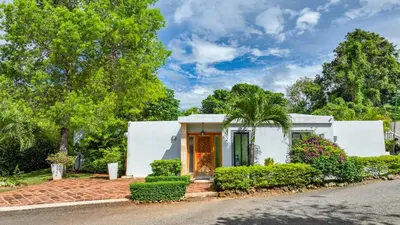 a white house with a palm tree and bushes at Casa Linda Villa 767 - Sosua in Sosúa