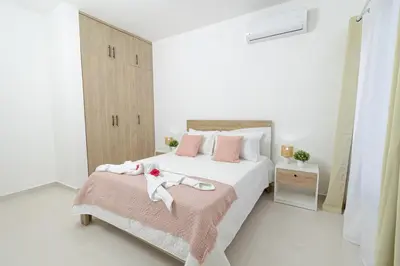 a white bedroom with a large bed with pink pillows at Modern 1BR Retreat Central Bayahibe Sunshine in San Rafael del Yuma