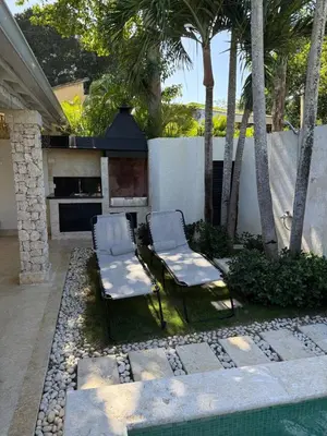 two chairs and a fireplace in a backyard with palm trees at Juan Dolio House 2BR y Patio in Los Corrales