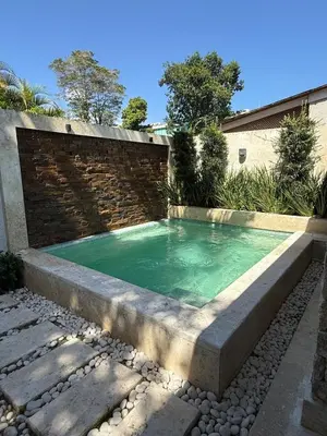 a swimming pool in a garden with a brick wall at Juan Dolio House 2BR y Patio in Los Corrales