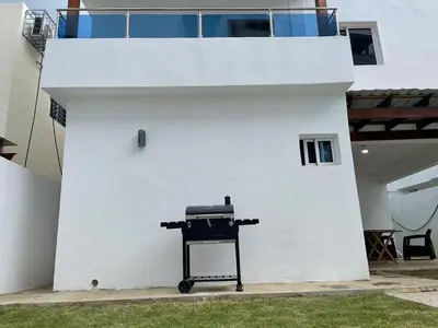 a barbecue grill sitting next to a white wall at Villa súper cómoda 3 habitaciones con piscina in Juan López