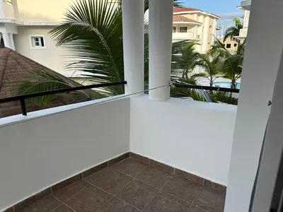 a balcony with white walls and a palm tree at The best place to rest, Arenas del Caribe in Punta Cana