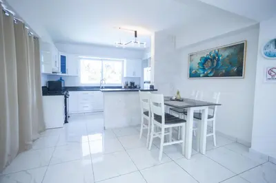 a white kitchen with a table and chairs in it at Sosua Residence by CJDR in Sosúa