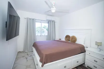 a white bedroom with a bed and a television at Sosua Residence by CJDR in Sosúa